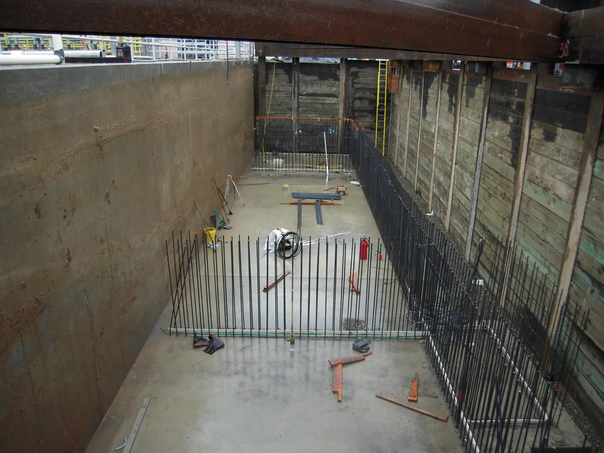 Tank expansion inside a shored excavation — dowels and wall steel tied to the existing structure.